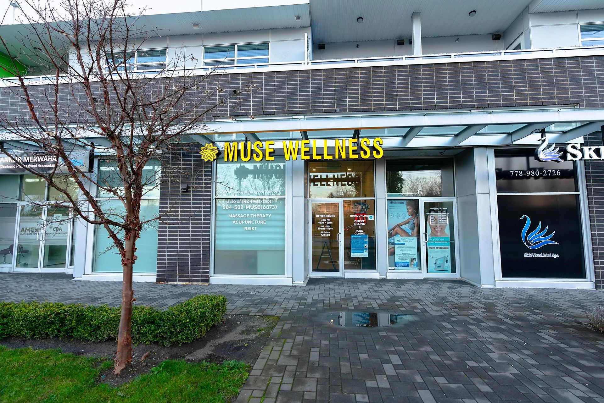 Street-level commercial storefronts including 'Muse Wellness' signage under a modern building