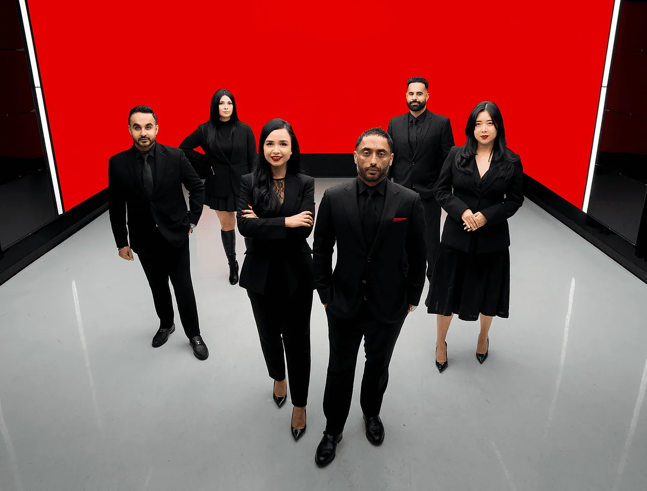 The Oberoi Group team in black in front of a red wall