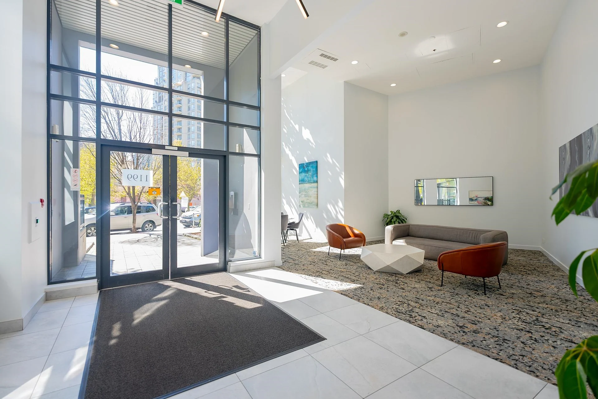 Bright condo lobby with glass doors, seating area and entry mat