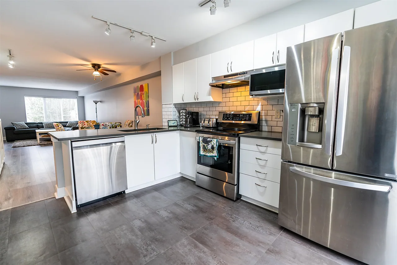 Kitchen with white cabinets opening onto a living area