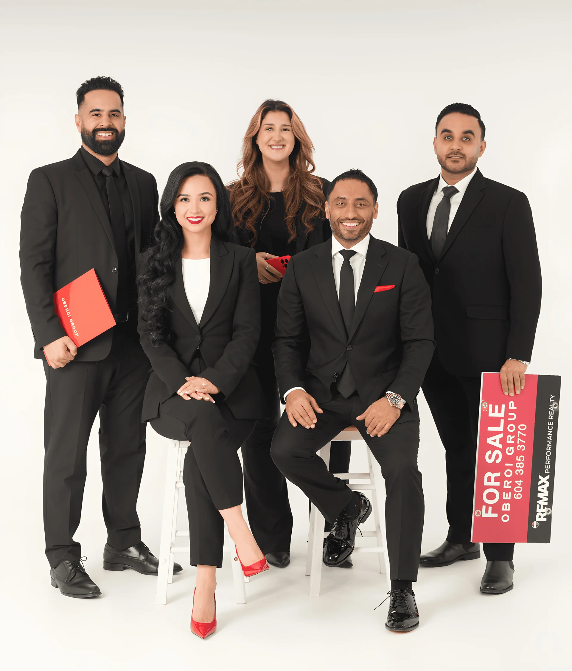 The Oberoi Group team, one holding a For Sale sign