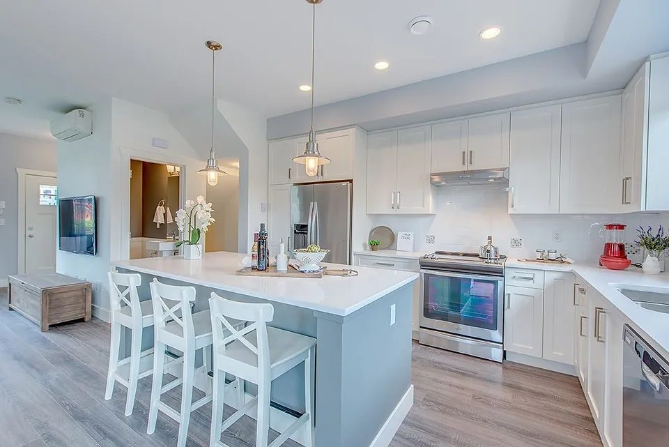 Bright kitchen with white cabinets, island with three white stools and stainless steel range