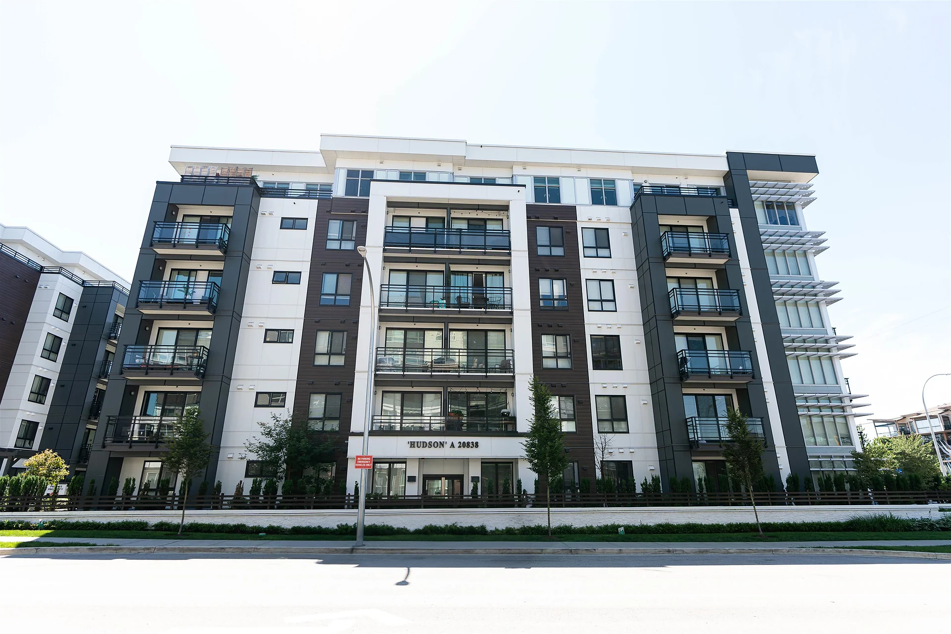 Six-storey modern apartment building with balconies and white-and-dark cladding