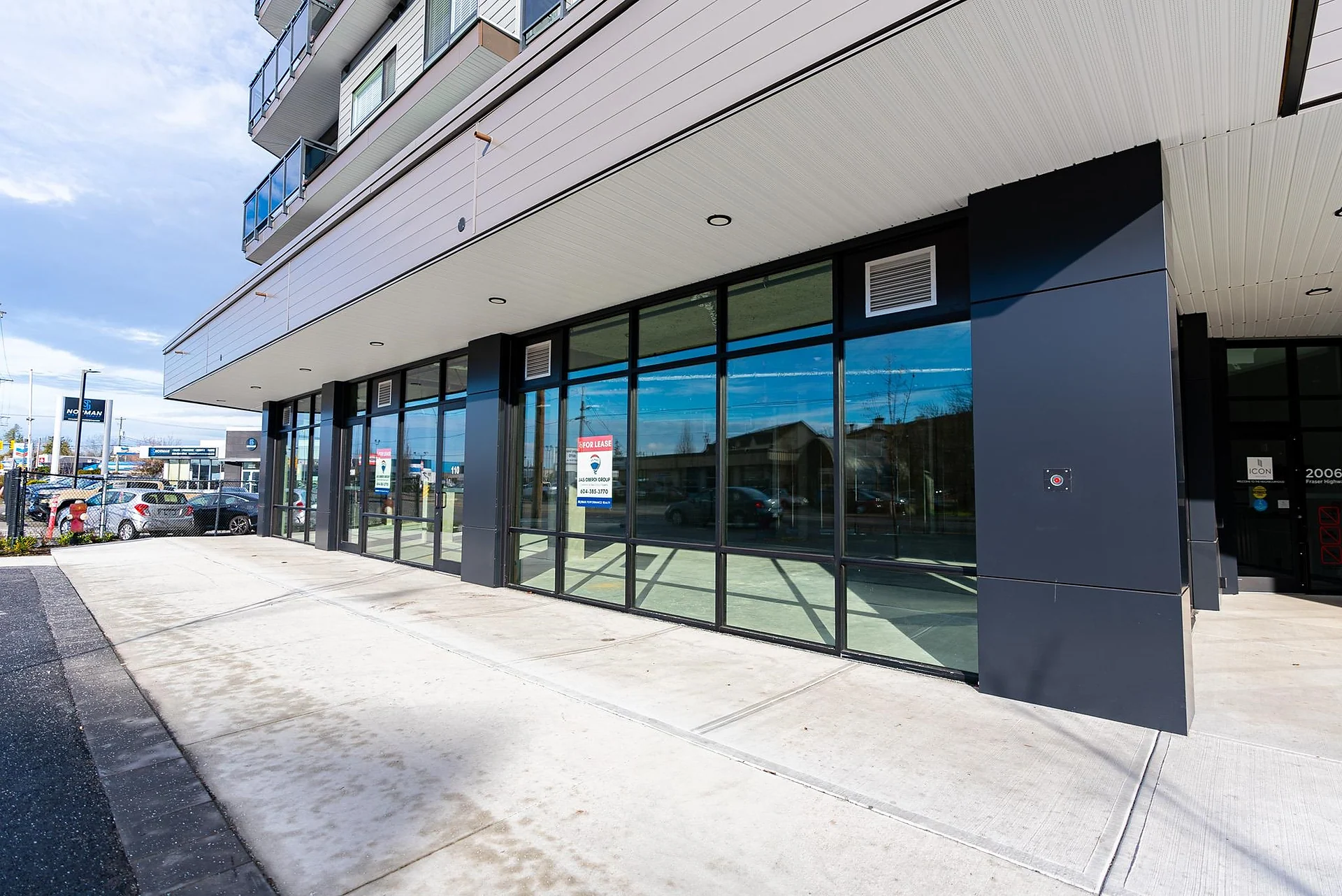 Ground-floor glass storefront of a modern mixed-use building along a sidewalk
