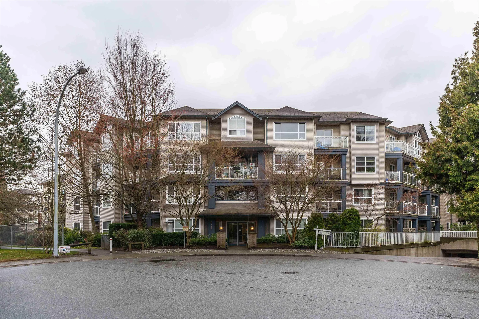 Four-storey condo building with trees and a cul-de-sac in front