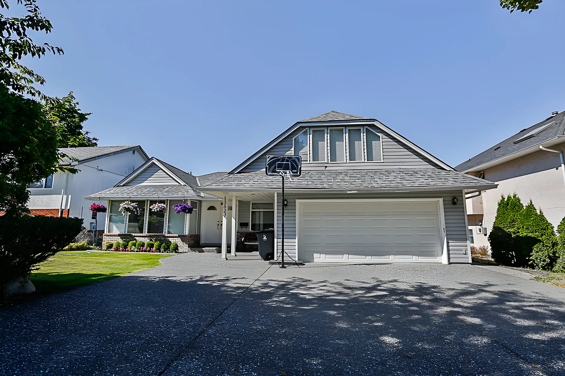 Single-storey house with gravel driveway, double garage and basketball hoop on a sunny day