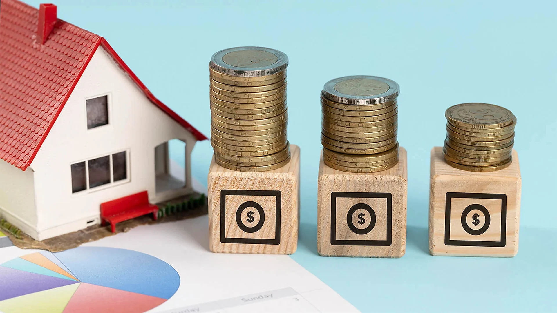 Model house beside stacks of coins and blocks marked with dollar signs, a pie chart behind
