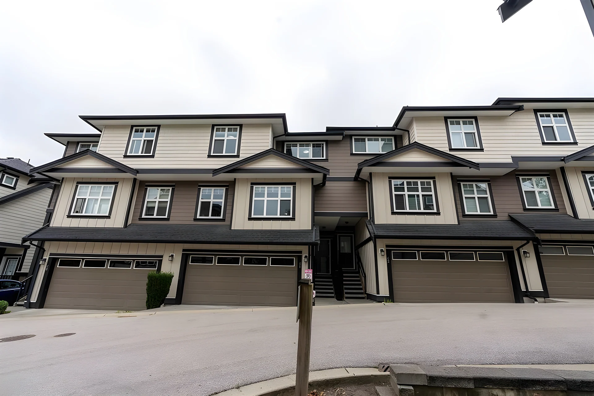 Row of brown three-storey townhouses with garages viewed from the street, low angle