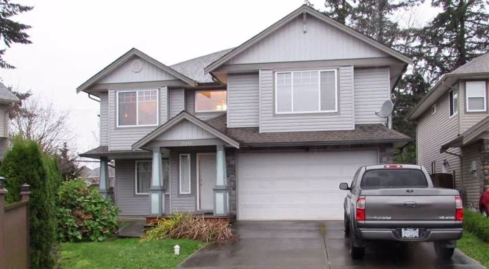 Two-storey grey house with a double garage and a grey pickup truck in the driveway