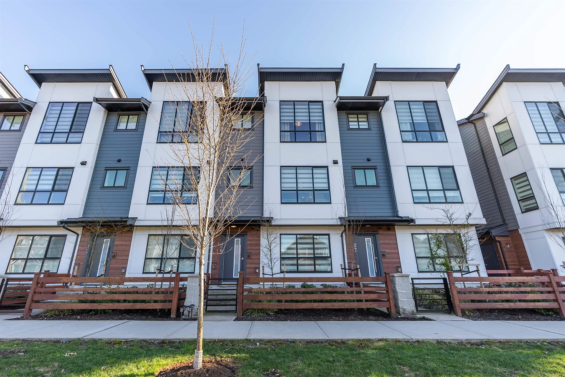 Row of modern three-storey townhouses with grey, white and red-brown trim